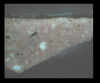 Fig.6 Cross-section through brown paint at the lower left edge, photographed at x260 magnification in ultraviolet light. From the bottom: salmon pink ground; opaque brown paint; varnish