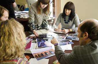 A group sit and look at some print outs in a Learning Outreach discussion