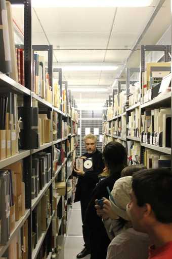 A member of Tate's archive leads a group around the archive, showing an item