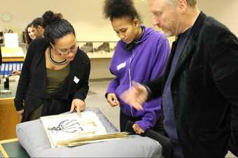 Three visitors look at an opened sketchbook in Tate's archive