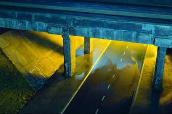 film still from Mark Leckey Dream English Kid, showing concrete bridge over a bypass lit up yellow.