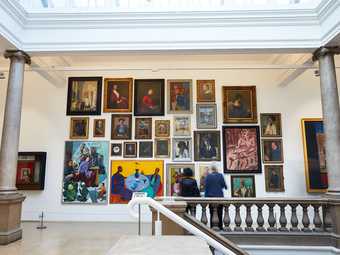 Dense gallery display of hanging paintings