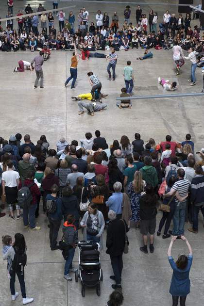 Crowd watches damcers in the turbine hall, taking photos of the performance