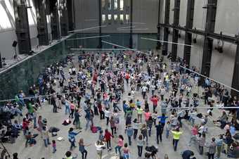 a group of visitors standing and dancing in the turbine hall