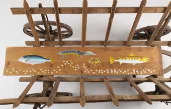 view of a wooden cart with two fish, a frog and a newt painted onto the chassis