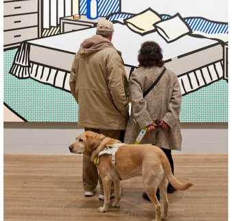 two people stand in front of a Lichtenstein artwork with a guide dog
