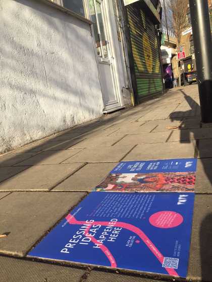 Two vinyl floor stickers on the pavement, one with the a headline that reads 'Pressing Ideas Happened Here' next to a dot on a map labelled Black Ink Collective.