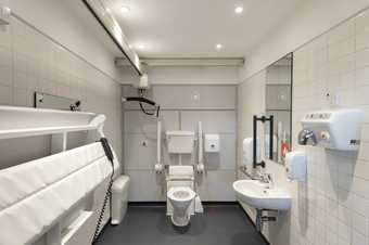 the inside of a changing places accessible toilet. The room includes a hoist.