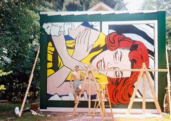 Roy Lichtenstein poses for the camera in front of Girl at Window (1964), made for the New York World's Fair, Flushing Meadows