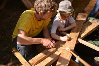 A man and a child make something together out of wood