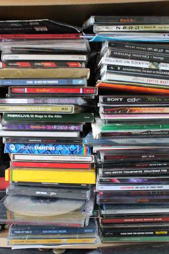 Two stacked piles of music CDs