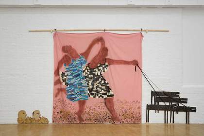 A large installation made of three main parts: two cut out paintings of heads on the floor, a large pink bedsheet with a painting of two Black women holding hands and dancing or running, and cut out paintings of four dogs that are attached to the larger p