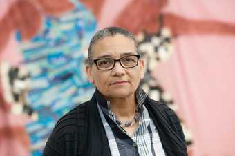 Portrait of Lubaina Himid with a painting in the backgound