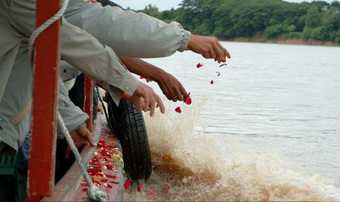People drop rose petals from a boat into the water