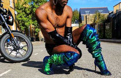 a male in high-heeled boots crouching in the road