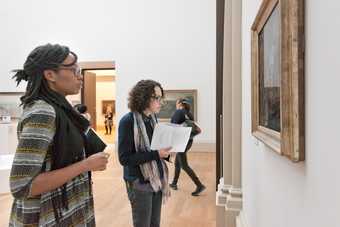 A teacher looking at an artwork in a gold frame