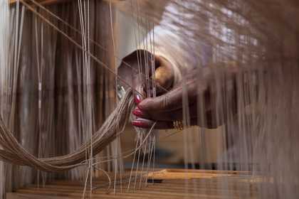 Hands weaving fibre using a loom