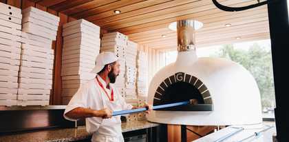 A picture of a man putting pizza into pizza cooker