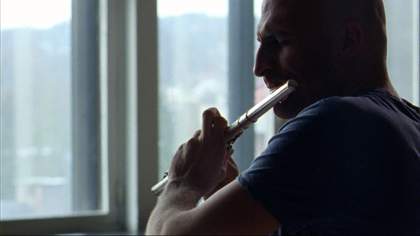 Film still showing a man playing the flute