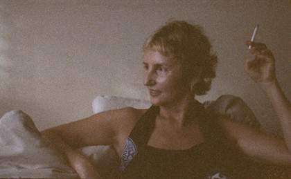 A film still showing a close up portait of a woman smoking, looking to the side
