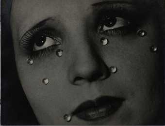 Black and white photograph of a close up portrait of a woman who has glass 'tears' on her face