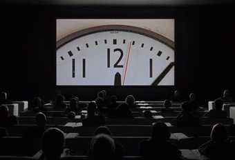 Picture of people watching a screen with a clock ticking