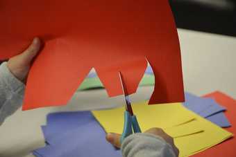 Photograph of a child's hands cutting coloured paper