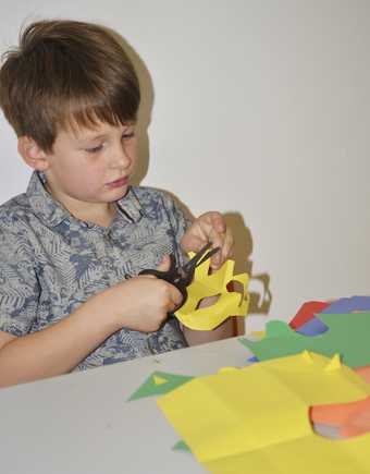Kid cutting paper to make his collage