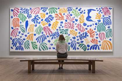 image of a woman sitting on a bench in front of a large Matisse cut-out in Tate Modern Henri Matisse: The Cut-outs exhibition