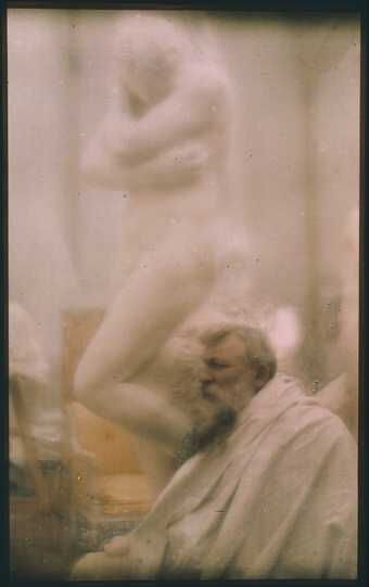 Colour photograph of Auguste Rodin in front of his plaster model