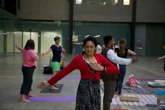 A meditation class in Turbine Hall with people standing on yoga mats