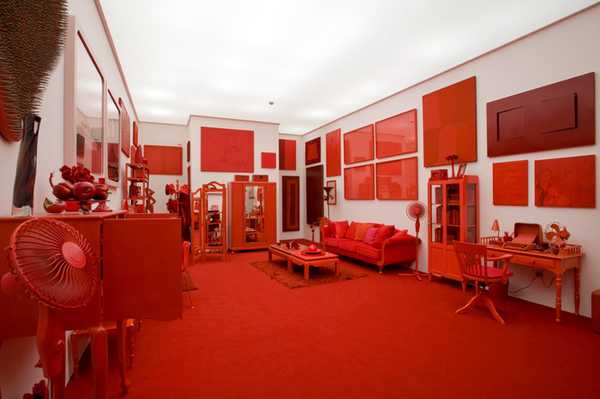 A room of entirely red furniture and wall art, except white walls.