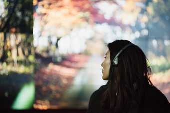 a women with headphones on stares at a projection