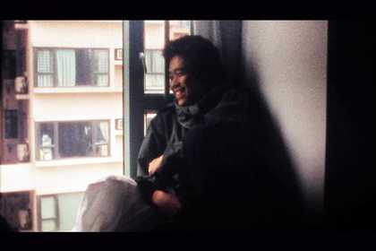 A person sits by a window smiles and looks out 