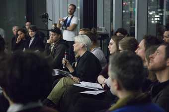 A woman from the audience holds and speaks into a microphone