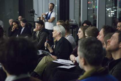 A woman from the audience holds and speaks into a microphone