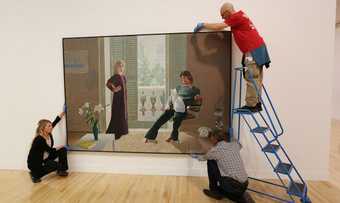Three people installing a painting