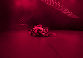 Human figures are seen on a floor intertwined with a hot pink filter on the room