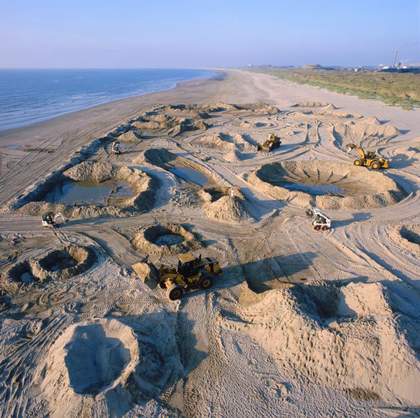 Diggers on a sandy landscape, working to make it look like the surface of the moon