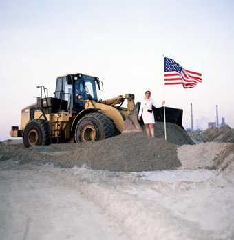 A woman placing an American flag on a sandy bank