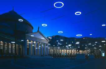 Colour photograph of an exterior building with circular lights above it in the sky