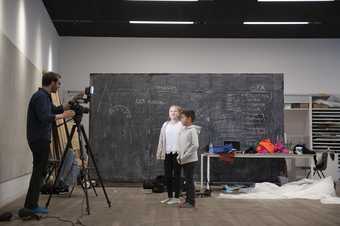 Two children standing in front of a blackboard getting their picture taken