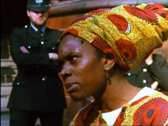 Film still of an woman wearing an African headscarf