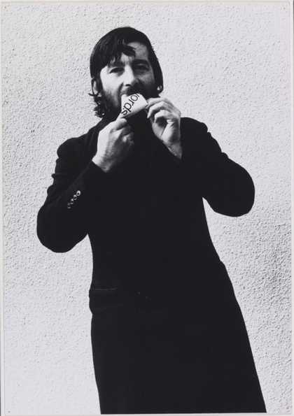 Photograph of Keith Arnatt eating a piece of paper with 'words' printed on it