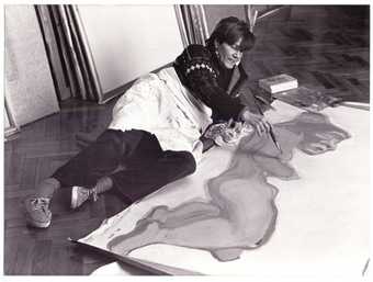 The artist painting whilst lying on her side on the floor