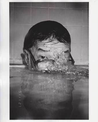Photograph Masahisa Fukase Bukubuku (bubbling) 1991 showing a man in a bath or swimming pool blowing bubbles