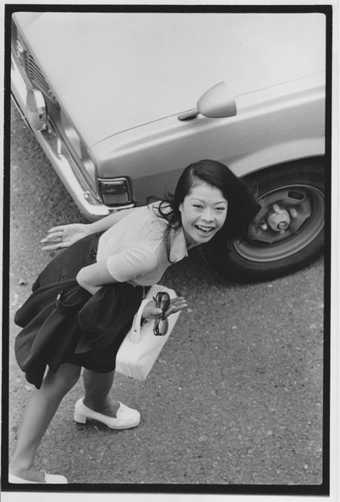 Masahisa Fukase's photograph, From Window 1974 showing a young woman carrying a suitcase photographed from above