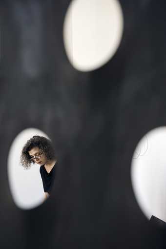 the artists seen through a hole in one of her artworks