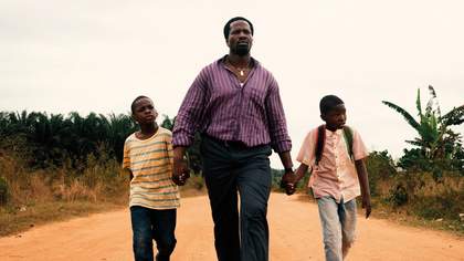 A father walks, holding twin sons by their hands