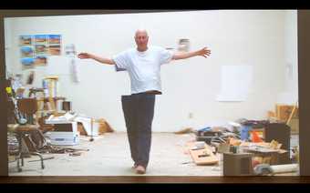 Film still of Bruce Nauman walking through his studio